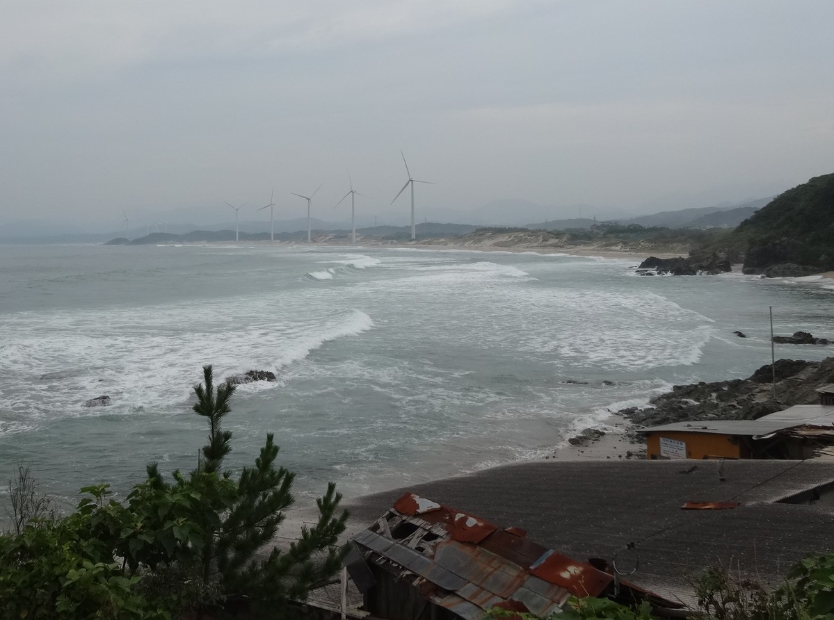 遠くに風車。続く砂浜と船小屋。